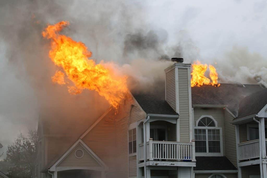 A house in flames thick smoke rising from the roof indicating a severe fire emergency