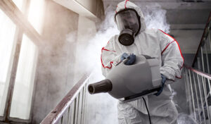 Image of a man in a gas mask and protective suit cleaning a room for biohazard cleanup and total restoration