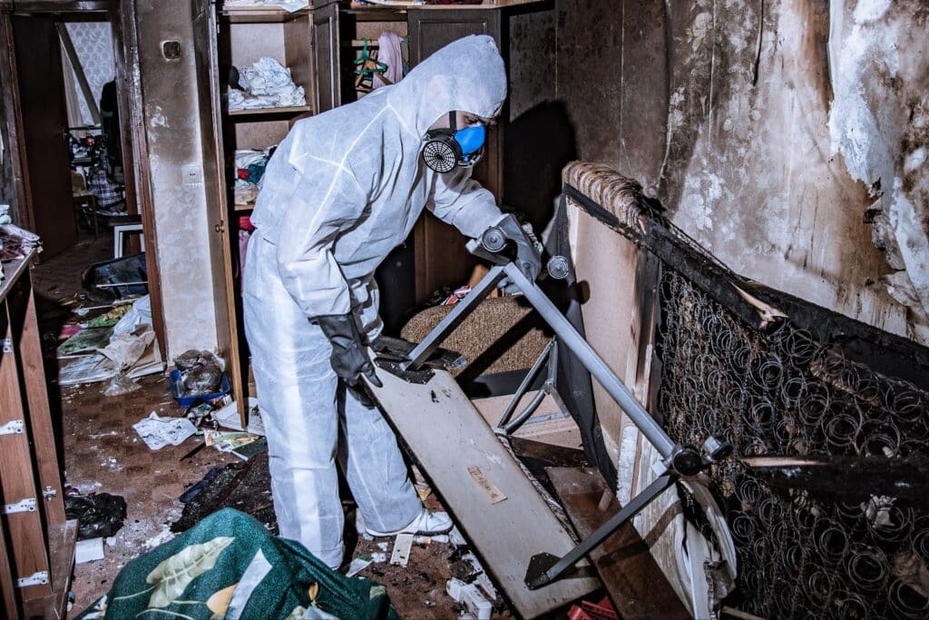 Man in white protective suit cleans room restoration services damage restoration companies cleanup, total restoration.