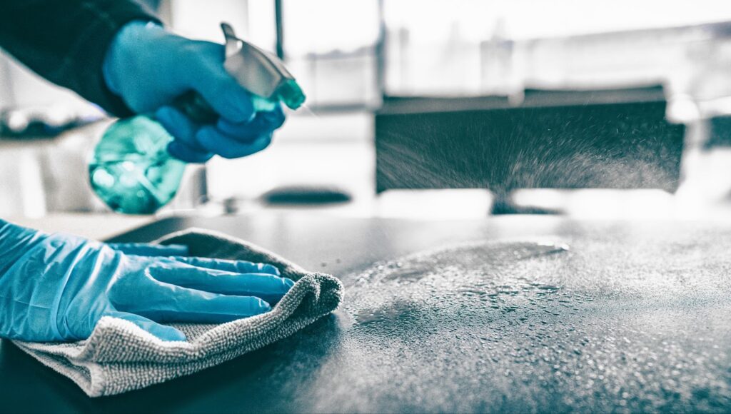 A person in blue gloves meticulously cleans a table as part of a disaster relief cleanup and restoration effort.