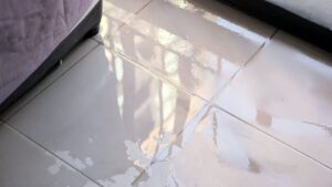 A white tile floor covered in water, highlighting the aftermath of water damage and potential health risks from contamination.