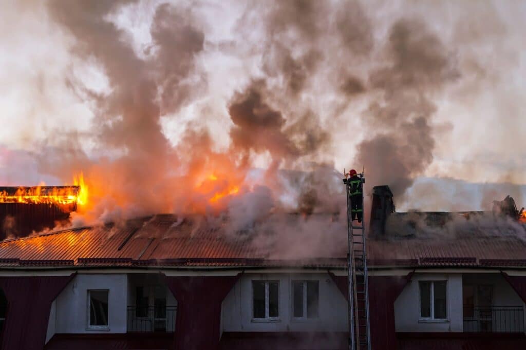 Firemen on a building roof combatting smoke, addressing smoke damage and cleaning efforts in nearby apartments.