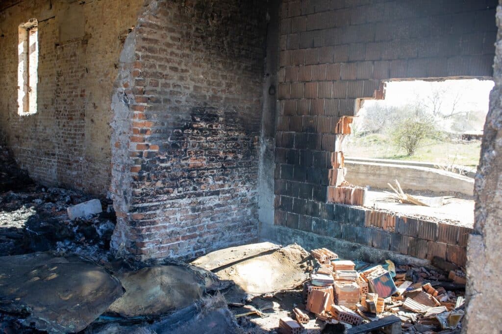 Interior of a charred building showing extensive smoke damage, highlighting the aftermath of a fire in an apartment setting.