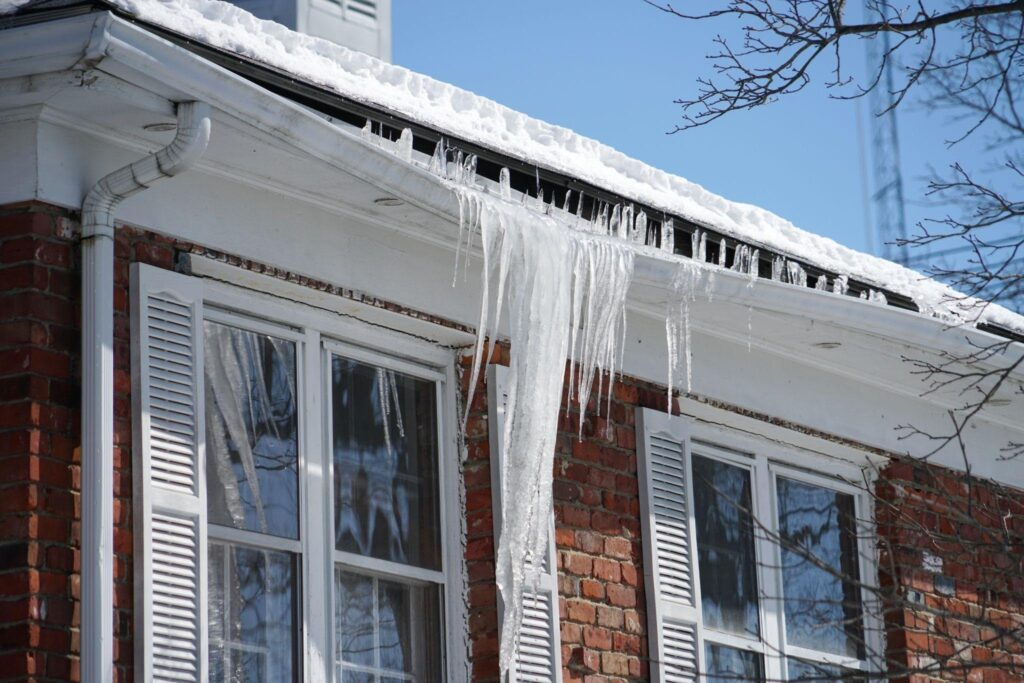 A layer of ice covering the roof of a residential building reflecting light and showcasing winter weather effects