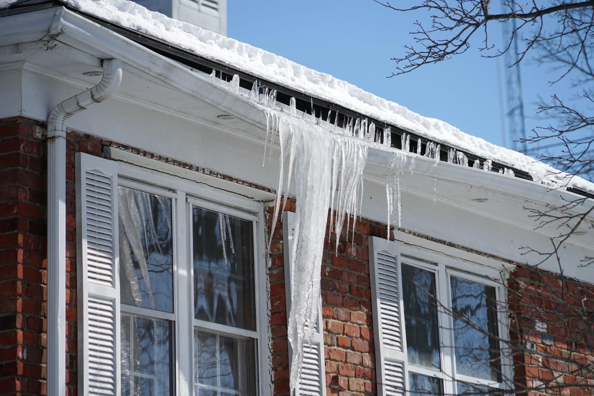 A layer of ice covering the roof of a residential building reflecting light and showcasing winter weather effects