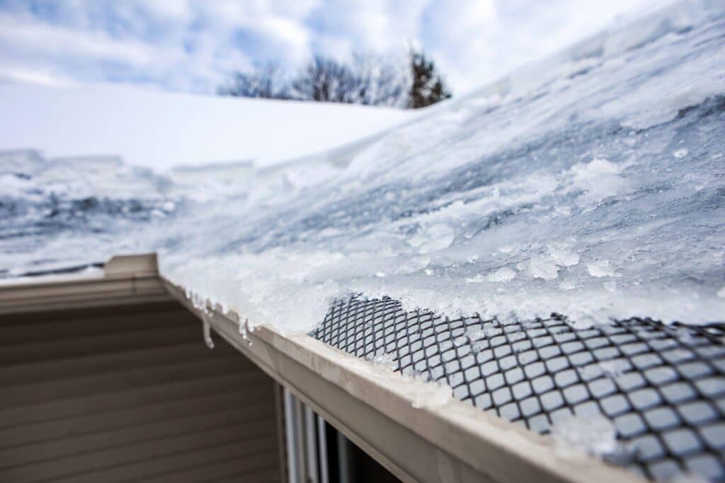 Ice accumulation on the roof of a house glistening in the sunlight indicating cold weather conditions
