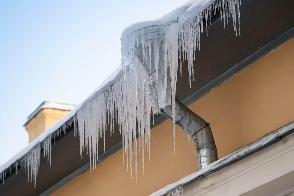 A row of icicles dangling from a residential roof highlighting the cold weather and seasonal changes